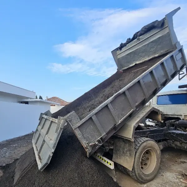 Camión tolva descargando áridos en una parcela de Colina